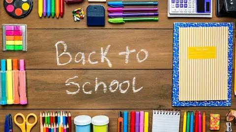 Back to school written in chalk on wood with various supplies.