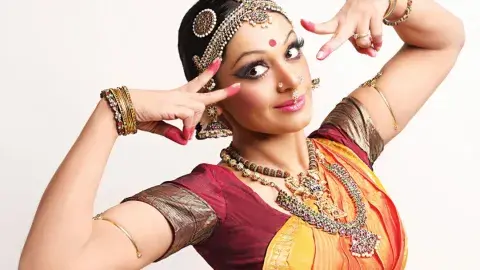 A woman is dancing dresses in a custom from a Bollywood Indian movie