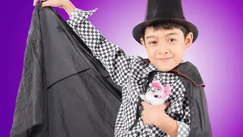 young boy in black cape and tall hat holding a stuffed bunny 