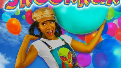A woman in braids and a hat is surrounded by balloons