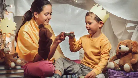 two children play in a tent with puppets