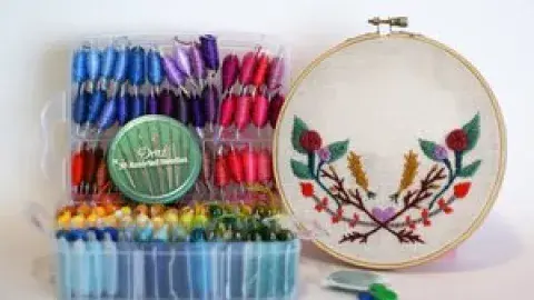 Various colors of thread spools on display next to an example of floral embroidery.