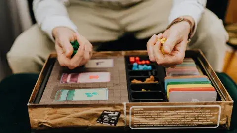 Person holding game board pieces playing a board game. 