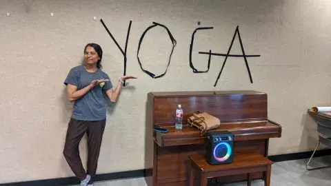 Yoga teacher pointing to the word yoga on the wall.
