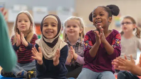 Kids sitting on the rug clapping