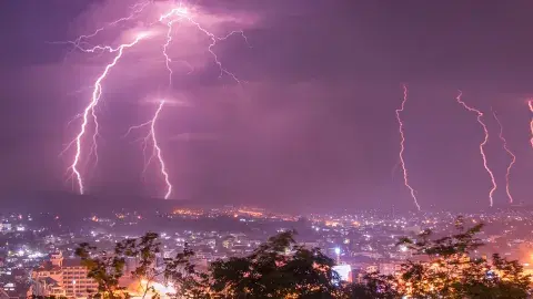 Lightning against a night purple sky over a city landscape