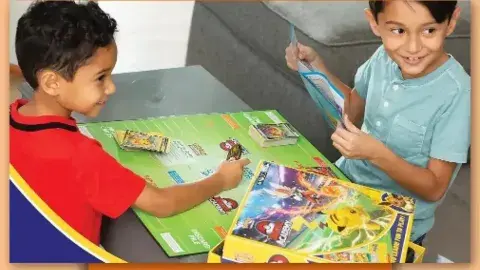 Two children playing Pokemon Battle Academy
