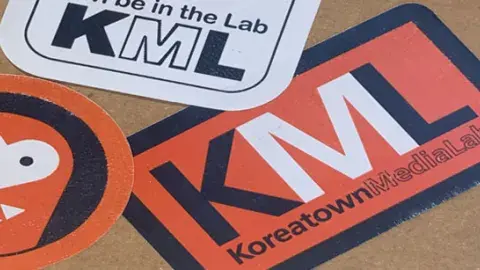 A collection of overlapping Koreatown Media Lab stickers on the back of a school notebook