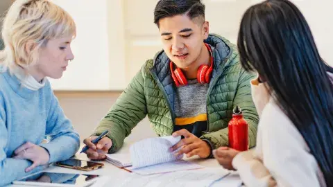 Teens collaborate at a table over papers