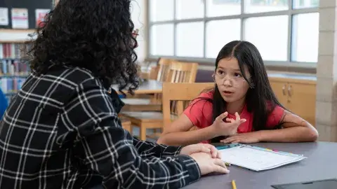 student talking to a tutor in a library