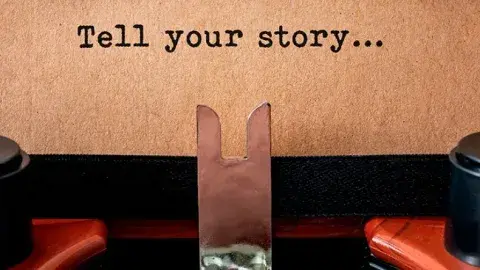 typewriter with a page that reads tell your story...