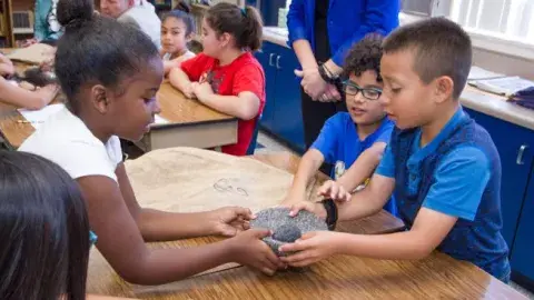 Children holding a stone molcajete.