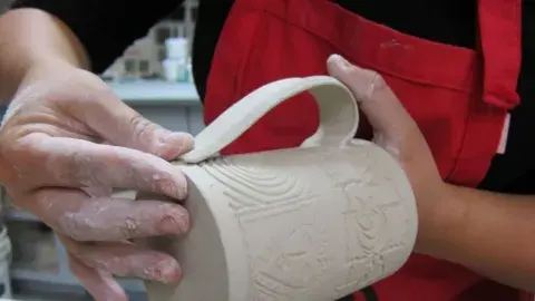 A person is making a ceramic mug