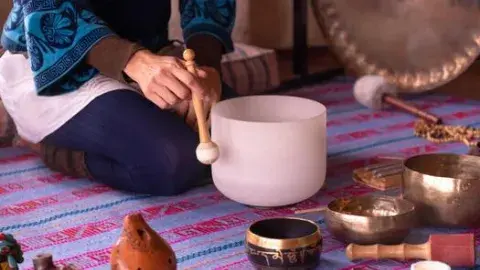Close up image of a woman's hands playing a quartz singing bowl
