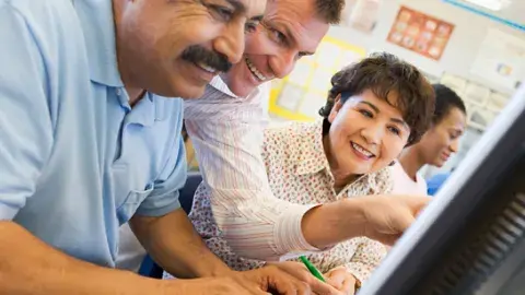 Adult students learning computer skills in a classroom.