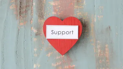 A heart shaped, made of wood with words “SUPPORT”