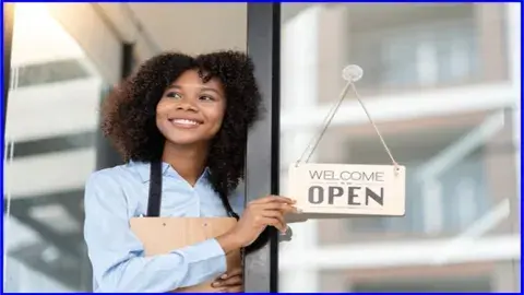 Woman holding an open sign front of a window