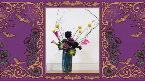 A spooky Japanese floral arrangement is displayed in the middle of a decorative spooky frame.