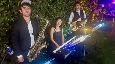 Three musicians with a tenor saxophone, keyboard, and guitar.