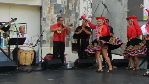 Musicans play music and colorfully dressed performers dance