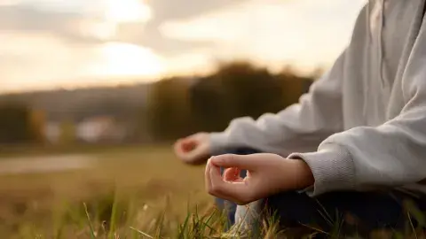Person meditating in a field.