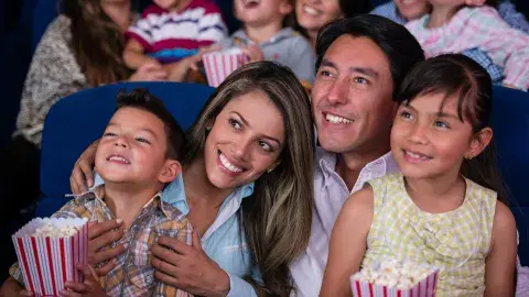 A smiling young family of four watch a movie