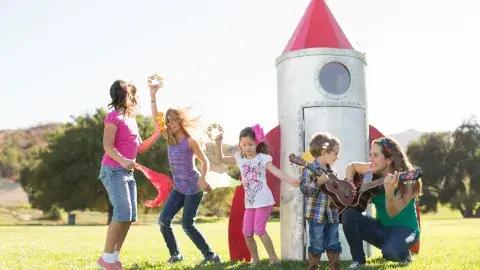 Kids dancing outside with Nathalia playing her guitar