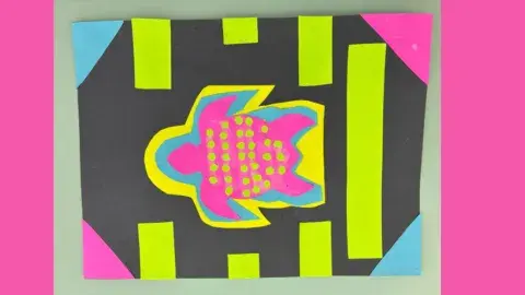 A neon pink turtle made out of construction paper surrounded by neon shapes on a black background.