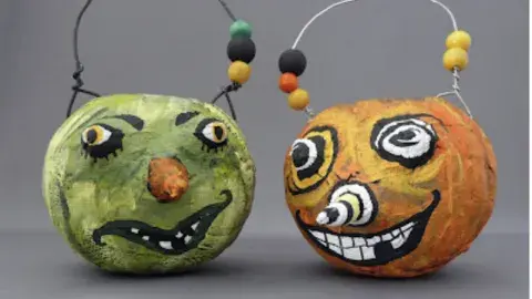 Two paper mache pumpkins posed side by side with spooky smiles.