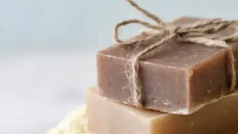 Two bars of soap stacked upon one another. The top bar is decorated with a jute twine bow tie.