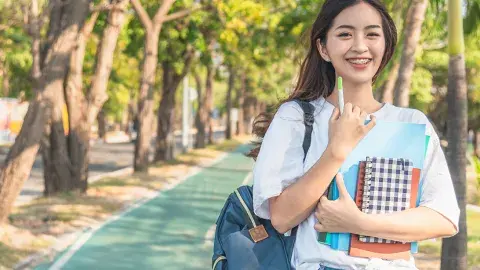 A young female student walking along the bike path of a college campus.