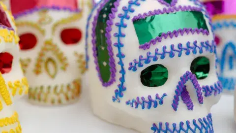 Several sugar skulls brightfly decorated are laid out on a table. 
