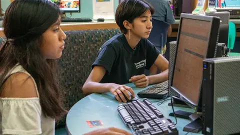 Two young people work on computers.