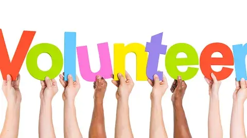 Hands hold up letters spelling "Volunteer"