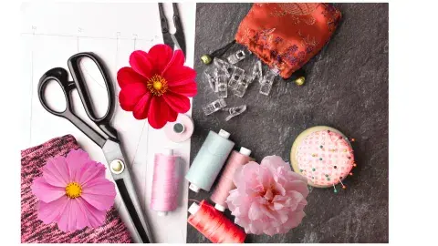 sewing supplies and flowers scattered on a table