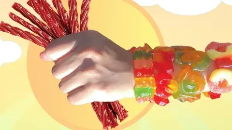 A hand holding red licorice wearing several bracelets made with gummy candies