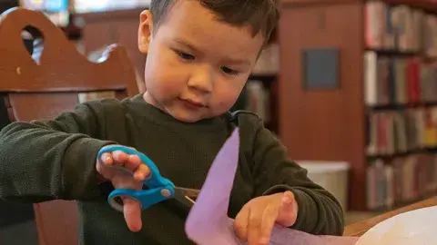 Child cutting paper with scissors