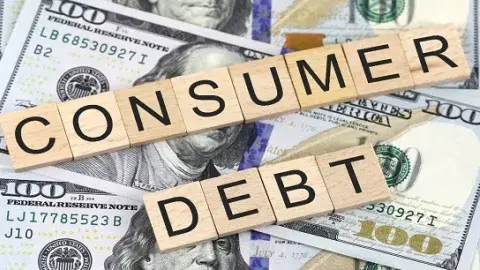 the word "Consumer Debt" spelled with wooden blocks on top of dollars.