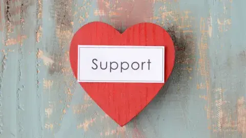 red heart with the word support written in black text