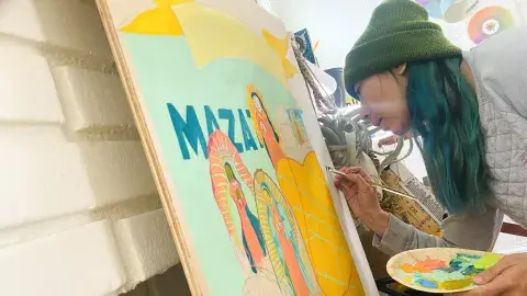 Artist paints on board while holding palette