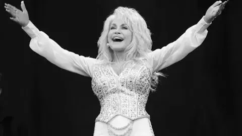 Dolly Parton with her arms up