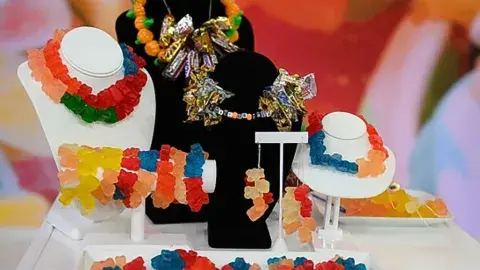 Colorful gummy bear candy jewelry displayed on necklace and bracelet stands.