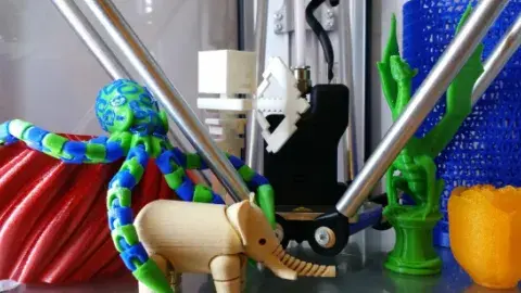 Colorful 3D-printed animals and objects displayed around a 3D printer.