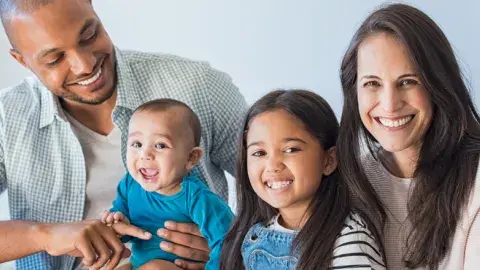 smiling family of four with parents, girl and baby boy