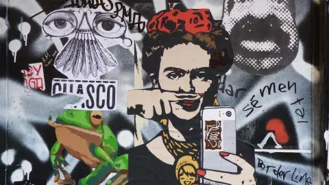 graffiti image of Frida Kahlo holding a cell phone surrounded by a collage of other images and writing