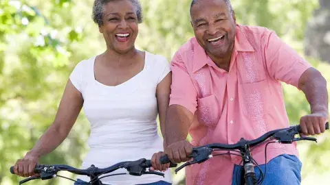  older couple biking with woman wearing a white shirt and man wearing pink shirt