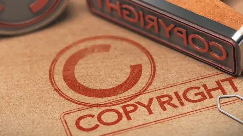 A copyright symbol on a piece of brown paper with a metal stamp placed on top.