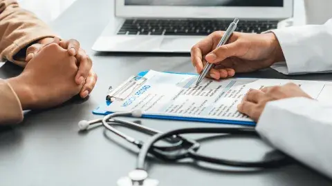 physician's hands filling out form for patient