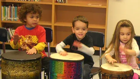 Three children playing the drums.