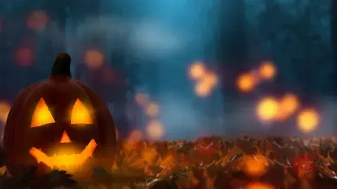 A smiling jack-o-lantern glows in the rain